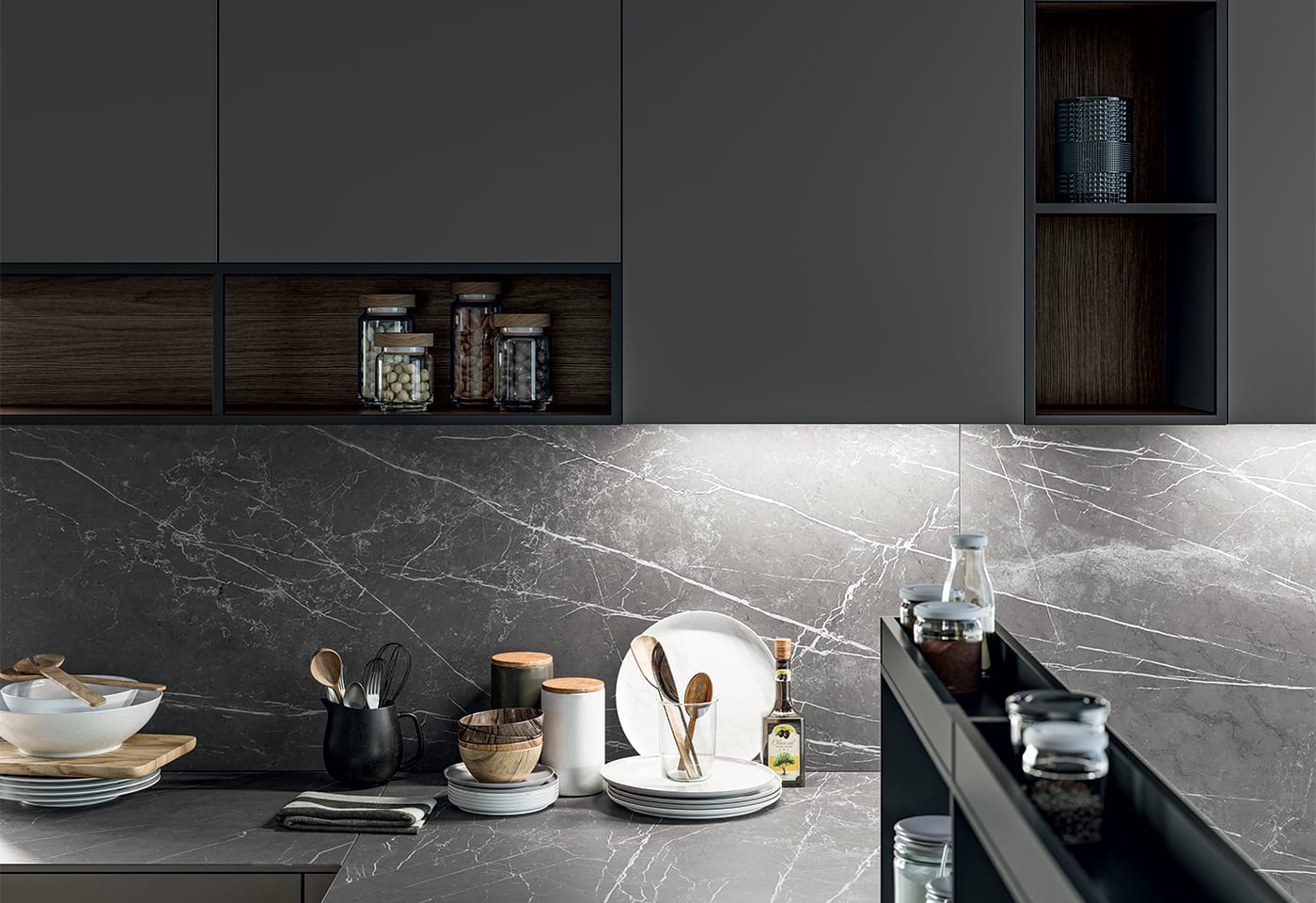 Närbild på köksbänk i kompositsten, samt väggskåp med köksluckor i mörkgrå laminat. Trädetaljer mellan skåpen.